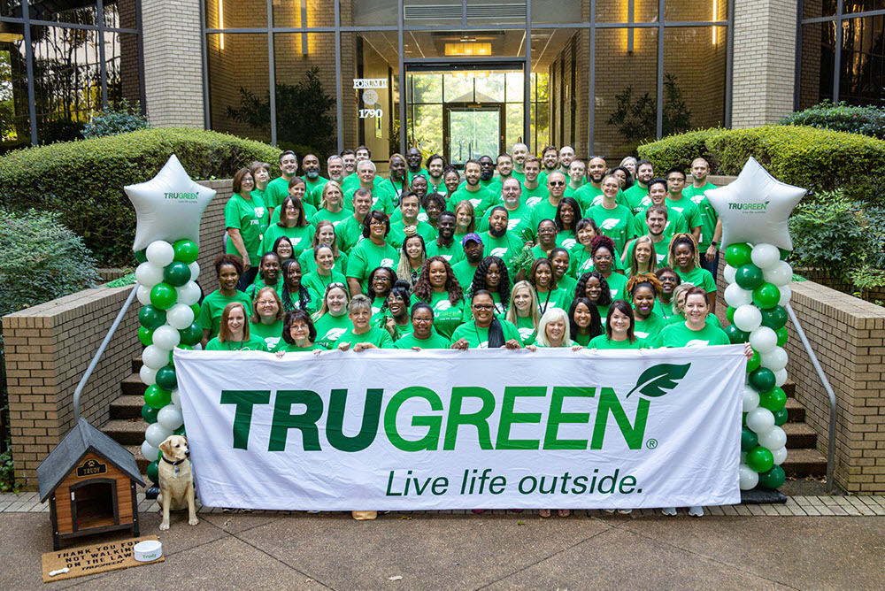 Trugreen employees holding company banner in front of headquarters