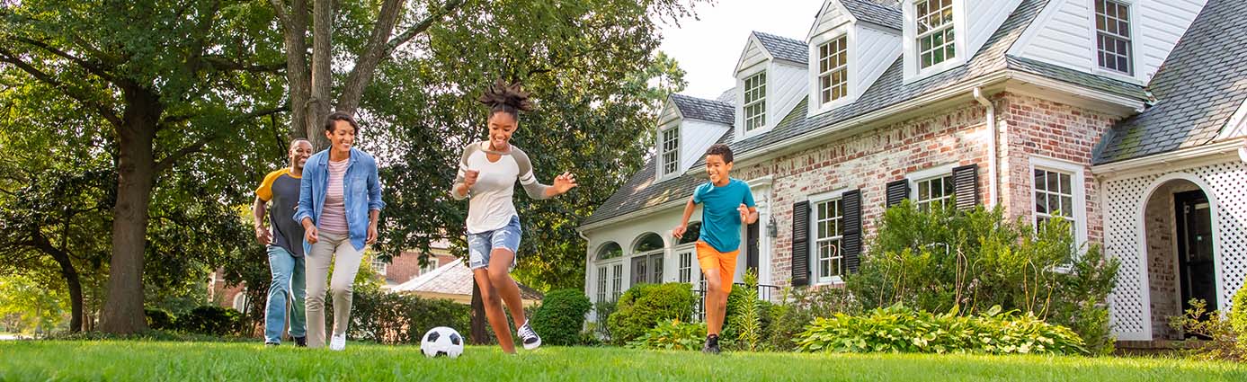 Family playing soccer on lawn