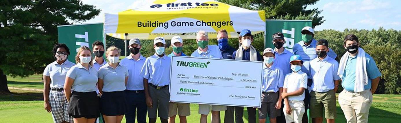 First Tee event  - golfers holding giant check