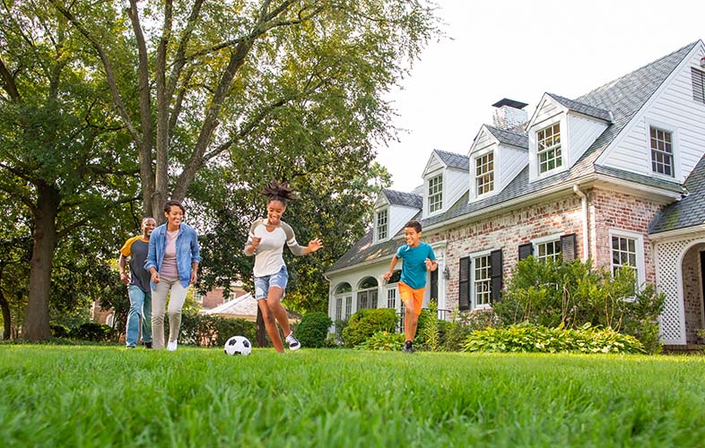 Family playing soccer on lawn