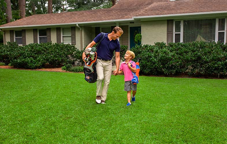 Father and son on lawn with golf bags