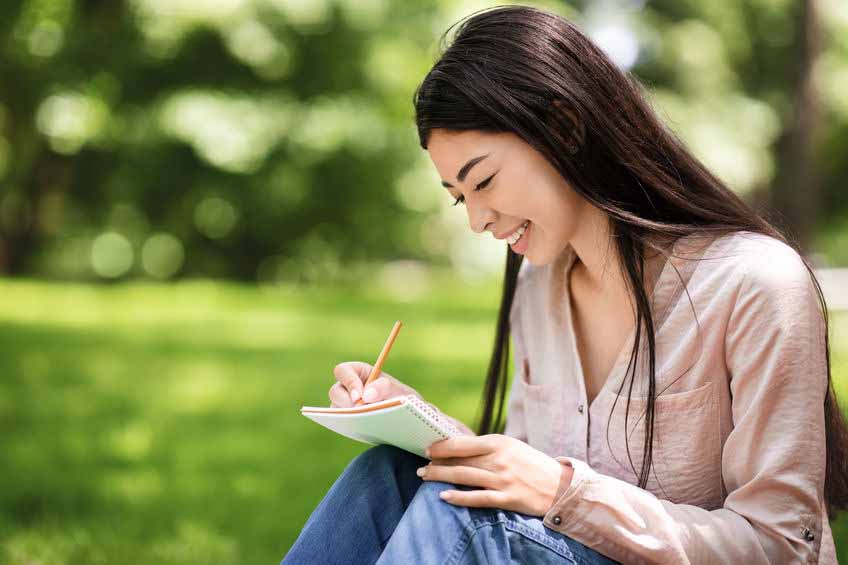 Woman writing in journal on lawn