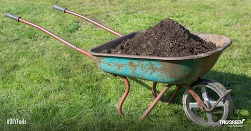 <p>Wheelbarrow full of dirt on green grass</p>