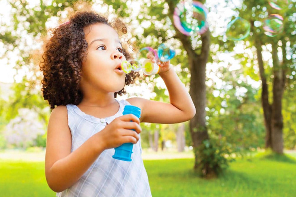 <p>Young girl blowing bubbles</p>