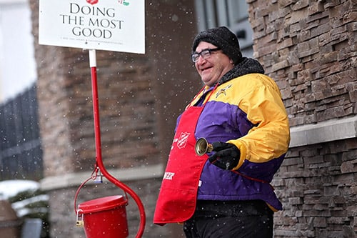 <p>Salvation Army bell ringer smiling</p>