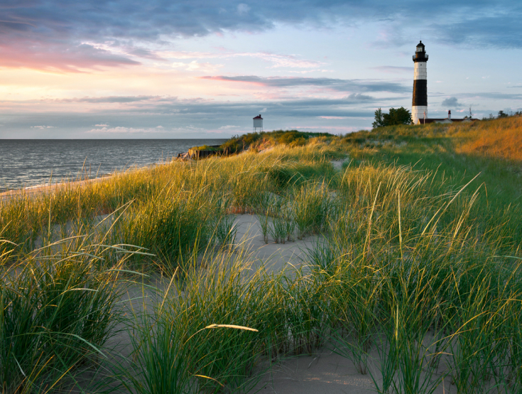 Lighthouse along the Michigan shore with green grasses in front of it