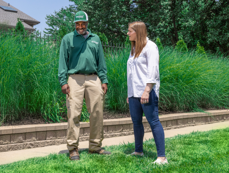 TruGreen specialist on a lawn talking to a customer