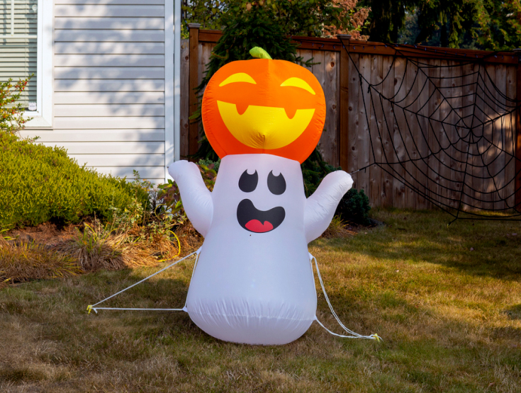 Ghost inflatable with a pumpkin on its head on a lawn