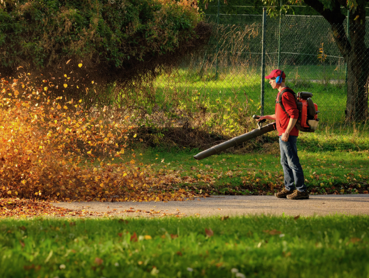 A man blowing leaves off a lawn