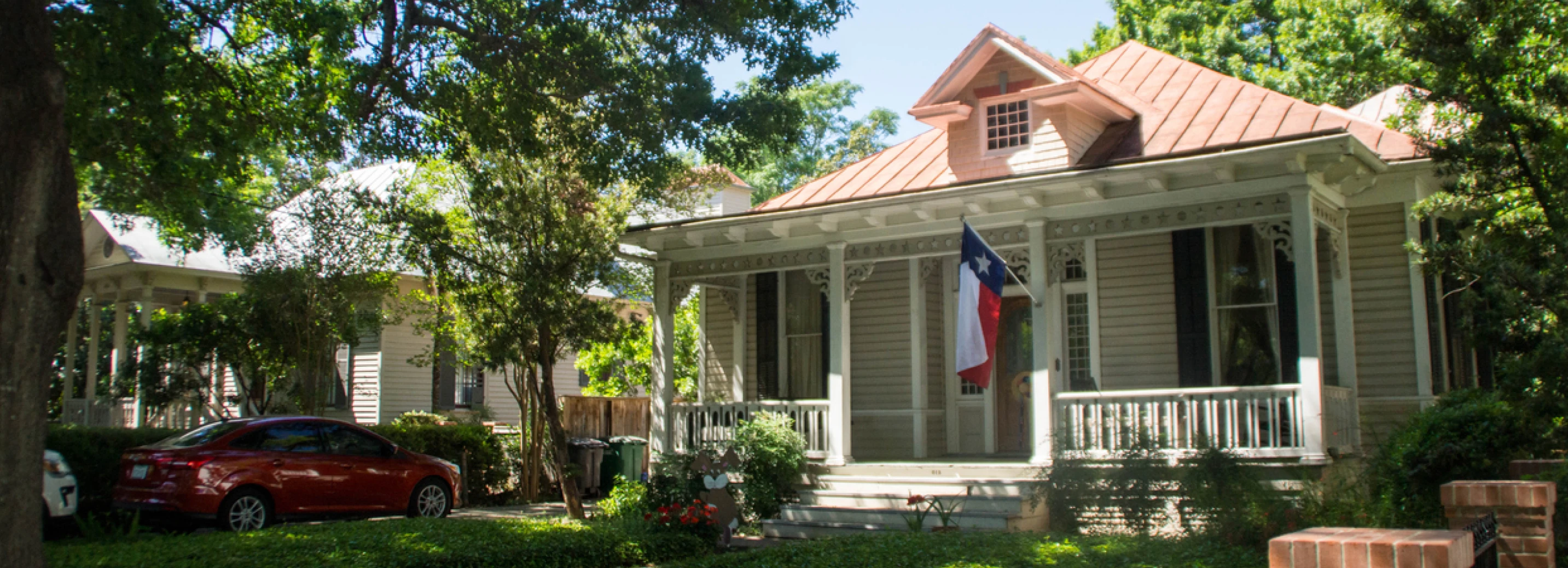 House with a Texan flag waving from the porch in front of a lawn