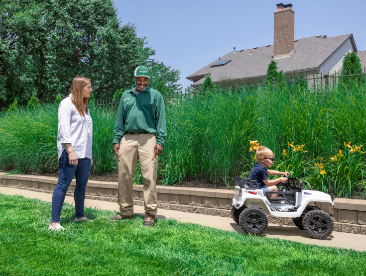 TruGreen specialist meeting with a customer on her lawn while her son plays