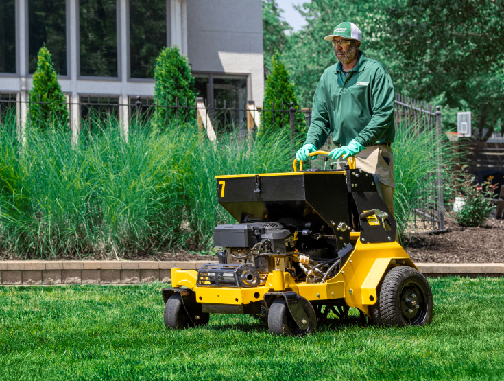 TruGreen specialist overseeding on a riding spreader