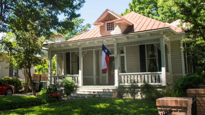 House with a Texan flag waving from the porch in front of a lawn