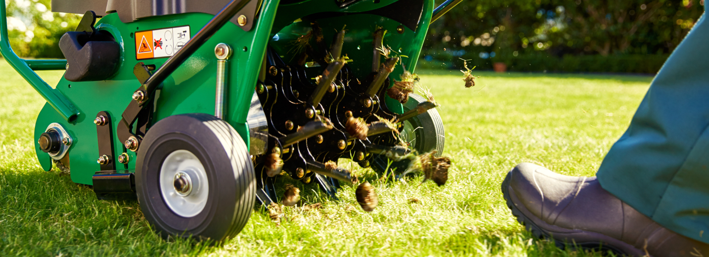 TruGreen specialist pushing a core aerator over a lawn