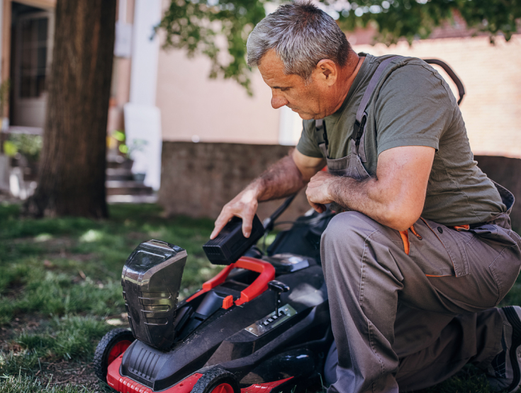 Man taking the battery out of an electric lawnmower