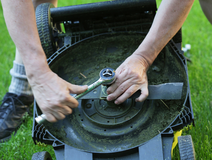 Someone doing maintenance on a lawnmower