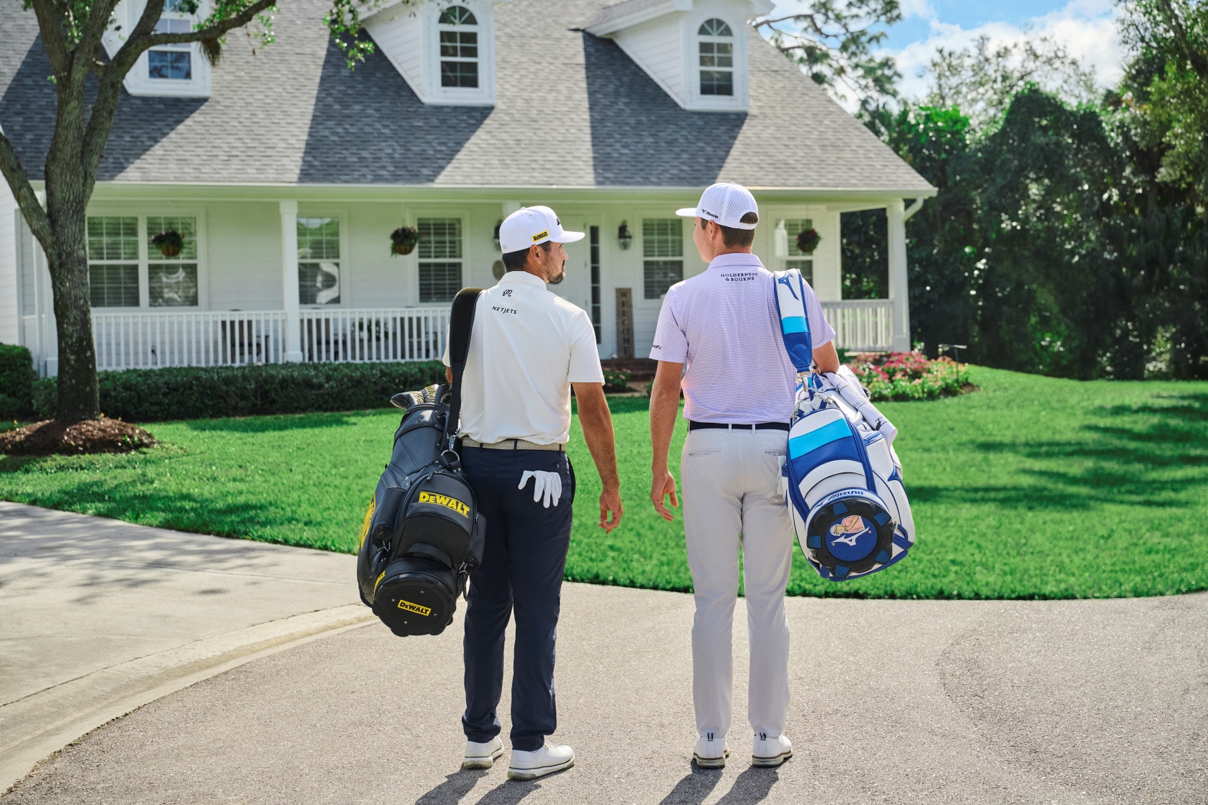 Jason Day and Ben Griffin standing with golf clubs looking at a golf course quality lawn.