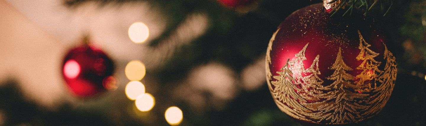 Close-up of a red Christmas ornament with gold, glitter trees on it