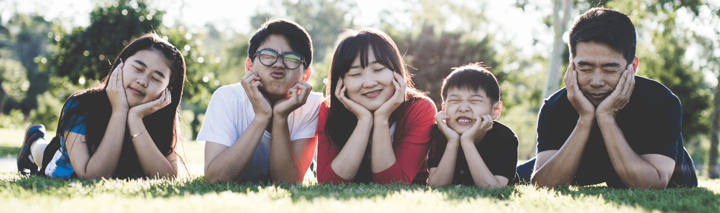 Family smiling and lying on a lawn